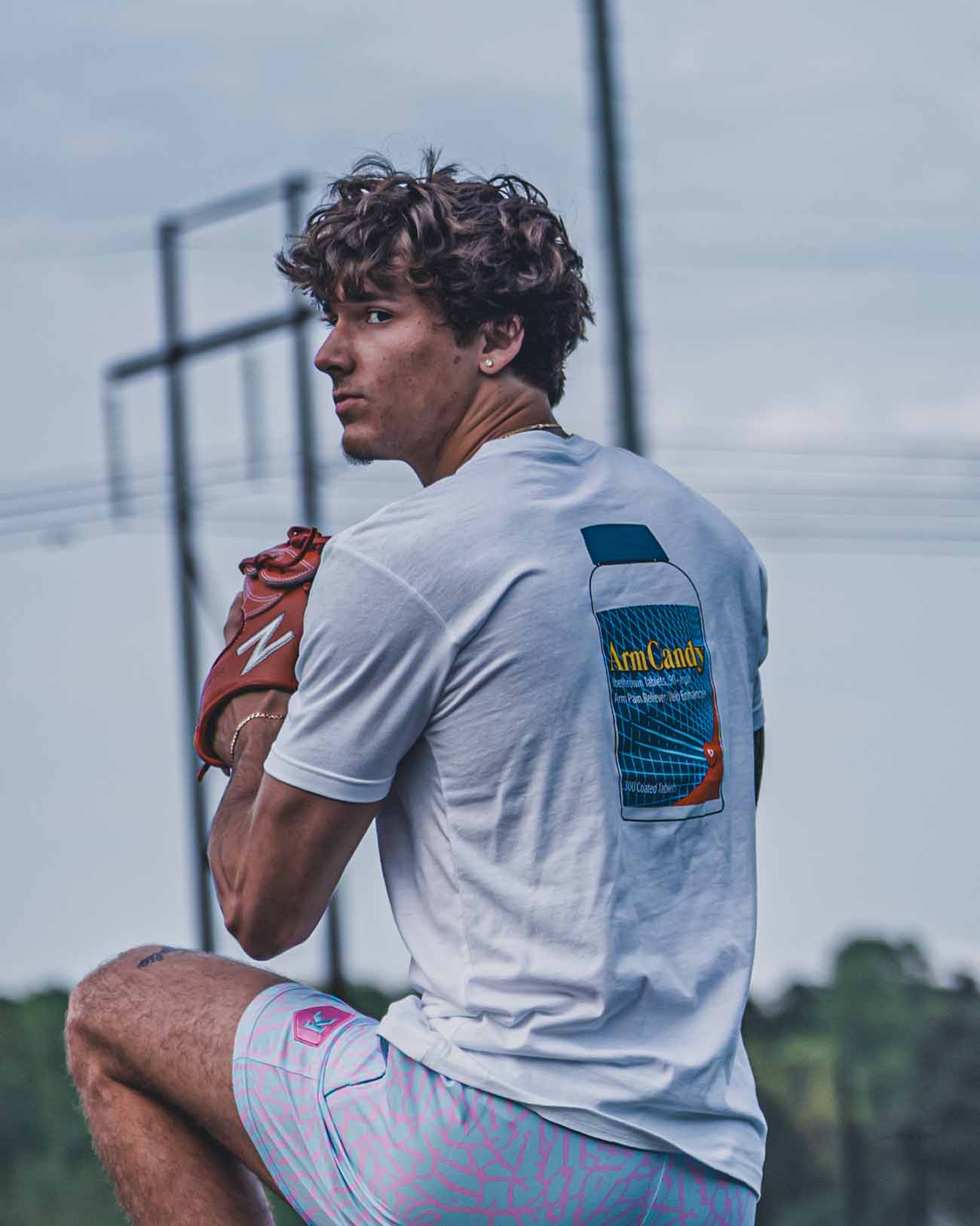 Tight shot of Pitchers Only Arm Candy white t-shirt with Ibethrowin graphic design on baseball player model from front.