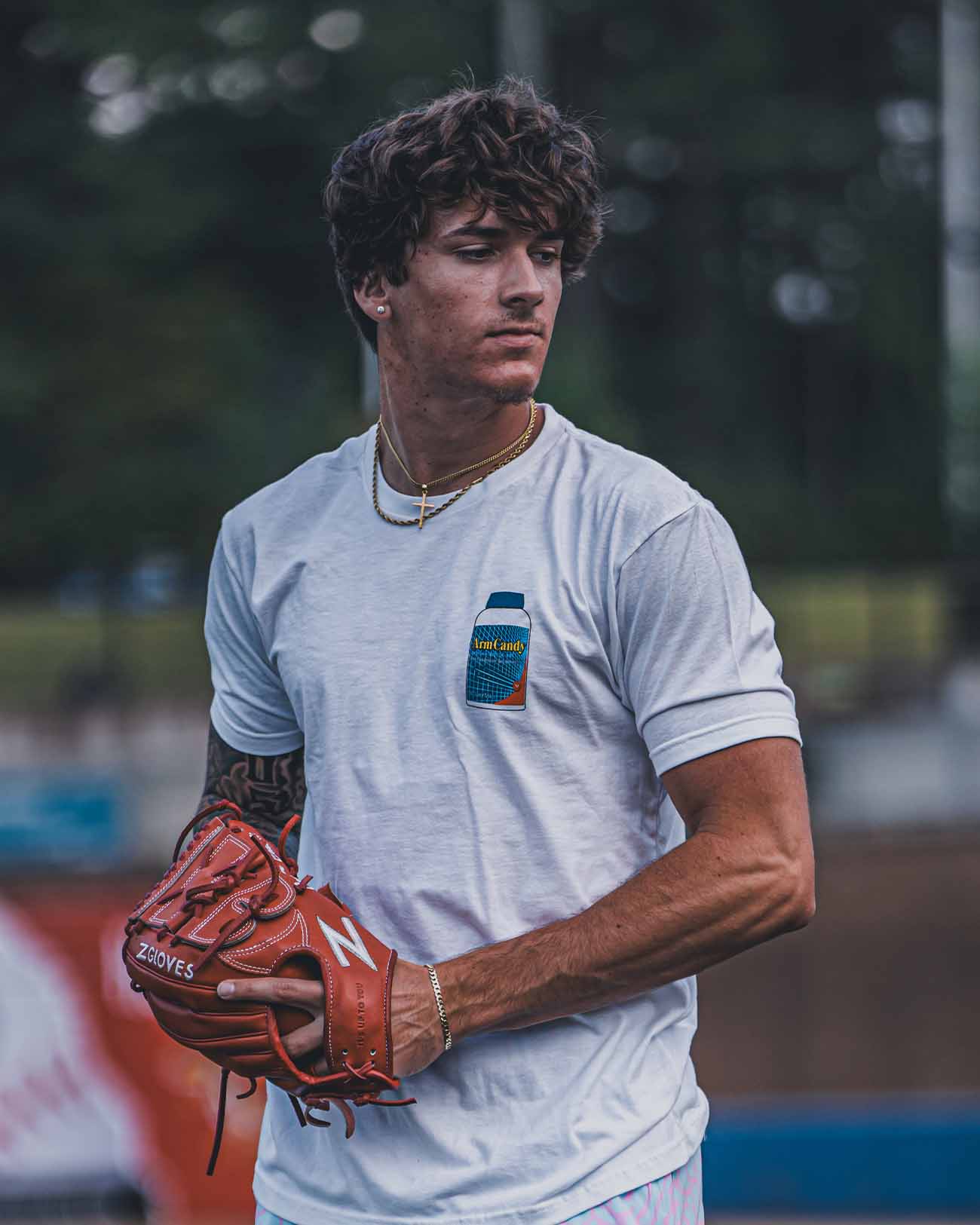 Tight shot of Pitchers Only Arm Candy white t-shirt with Ibethrowin graphic design on baseball player model from front.