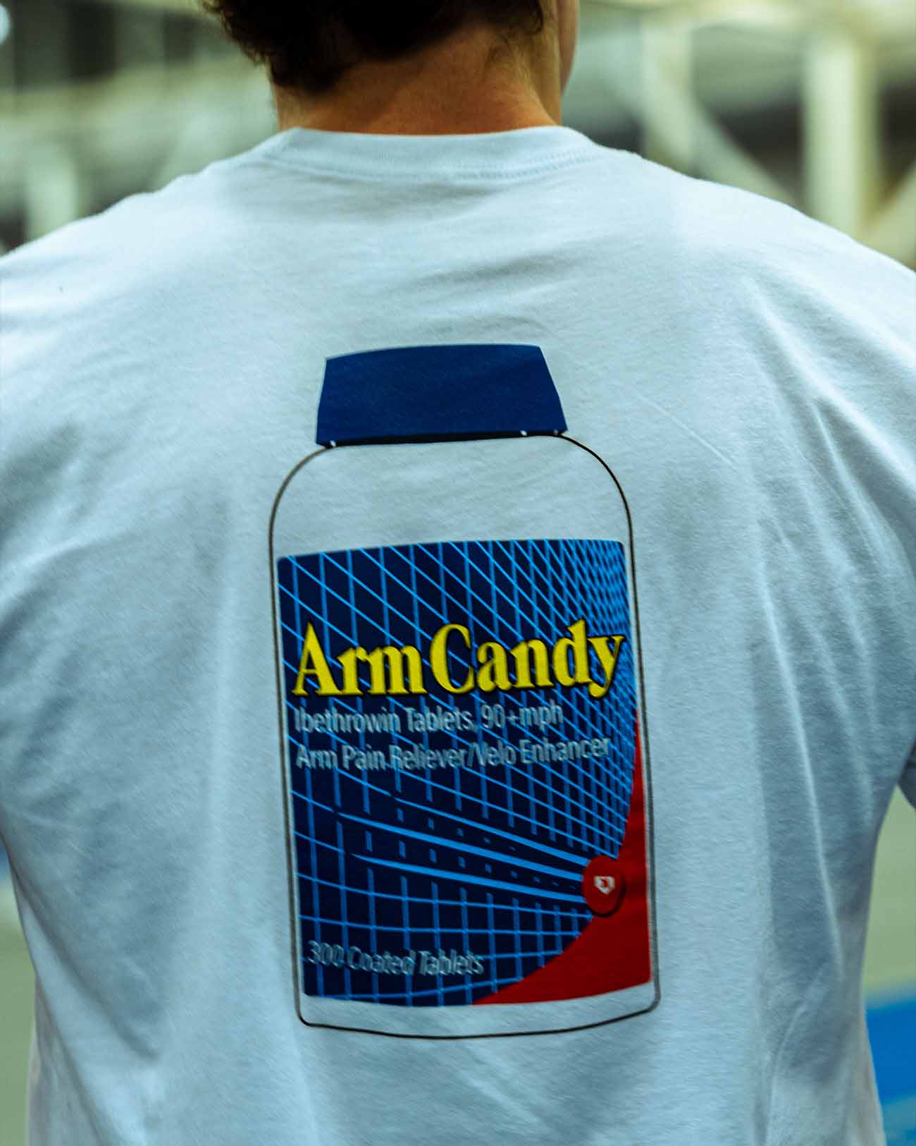 Tight shot of Pitchers Only Arm Candy white t-shirt with Ibethrowin graphic design on baseball player model from front.