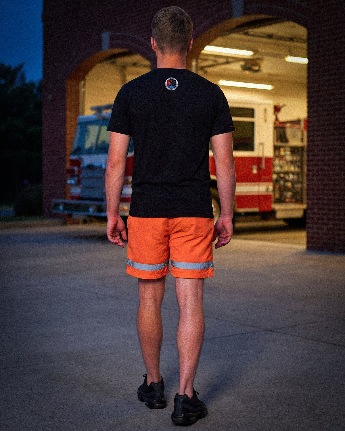 Back view of the First Responders Tee and Safety Orange Shorts walking toward the Kokomo fire station - Pitchers Only