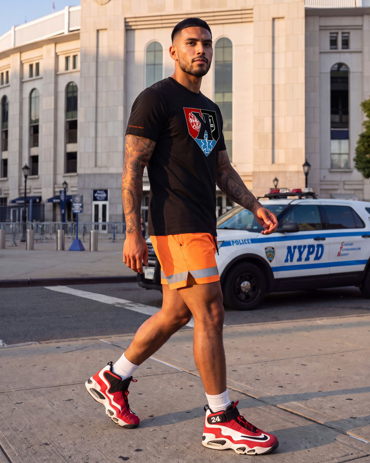 Model walking past an NYPD cruiser in the First Responders Tee and Safety Orange Shorts