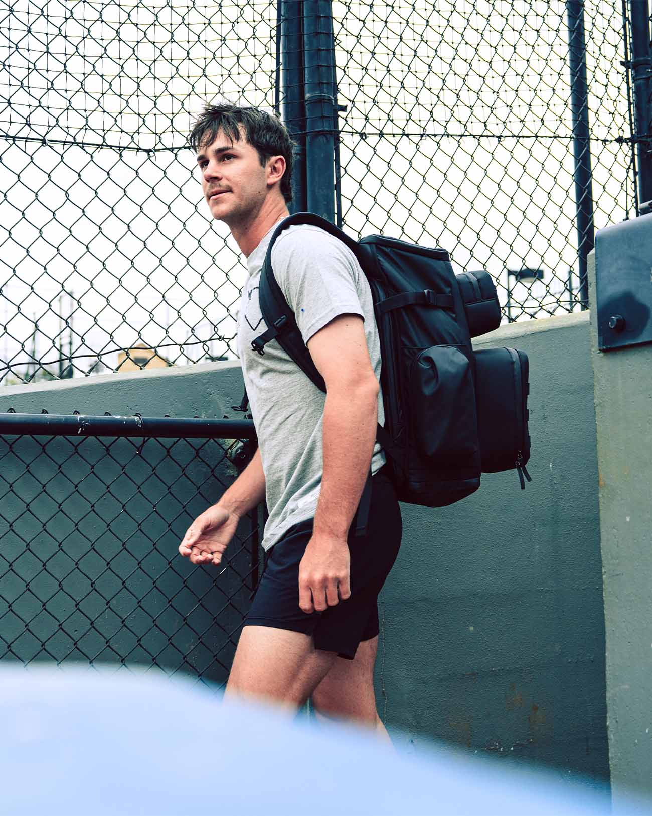 Baseball player walking with Pitchers Only Black Shove Day Bag on his back in side view.