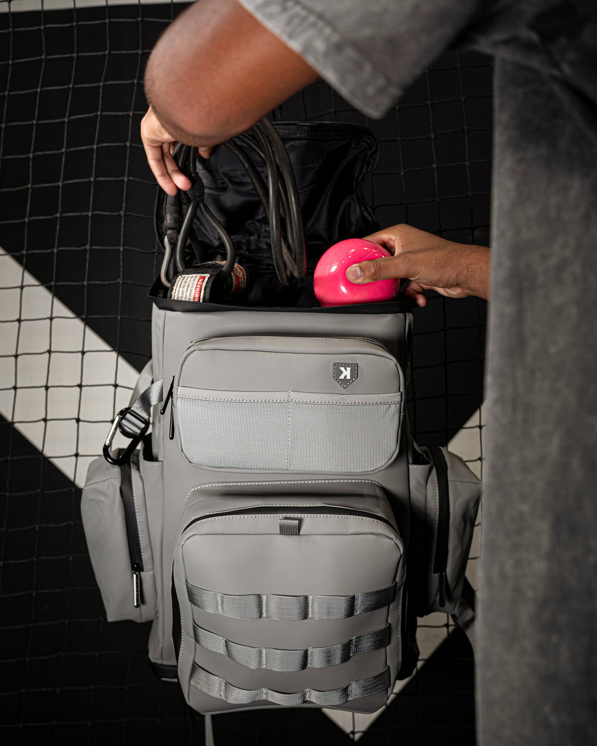 Baseball player loading gear into the top of the Pitchers Only Wolf Gray Shove Day Bag.